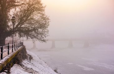 foggy morning near the bridge through the frozen river