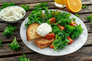 Breakfast Green Kale with poached eggs, feta cheese, tomatoes and toast. healthy food