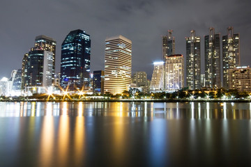 Fototapeta na wymiar Office building edge lake in Bangkok city at night.