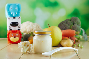 Jar with cauliflower puree near toys and fresh vegetables