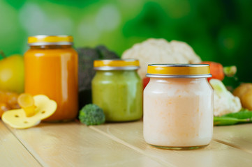 Jar with vegetable puree with spoon near fresh fruits and vegetables