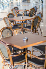 Tables and chairs in the cafe on the terrace. There are no visitors. In the background, you can see the pool. On standing ashtrays for smokers.