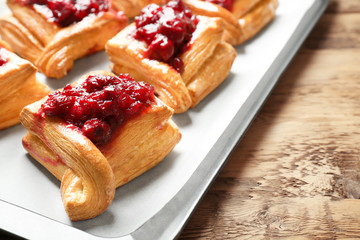 Tray with delicious puff pastries and cherry on wooden table