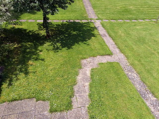 Wege und Pfade mit Steinplatten auf grünem Rasen im Sommer bei Sonnenschein in einem Garten in...