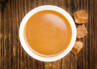 Portion of Caramel Sauce on wooden background (selective focus)