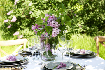 Beautiful table setting with lilac flowers decoration outdoors