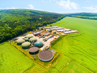 Aerial view over biogas plant and farm in green fields. Renewable energy from biomass. Modern...