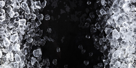 Pieces of crushed ice cubes on black background. Copy space, top view