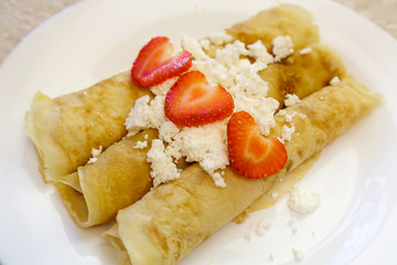 Dessert made from pancakes stuffed with cottage cheese and strawberries.