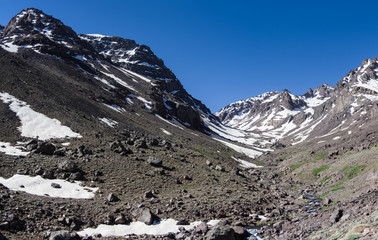 Fototapeta na wymiar TToubkal national park in springtime with mount, cover by snow and ice, Refuge Toubkal, start point for hike to Jebel Toubkal, highest peak of Atlas mountains and Morocco
