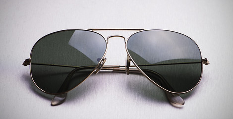 Close-up of dark sunglasses with metal frame on gray background. Horizontal studio shot.