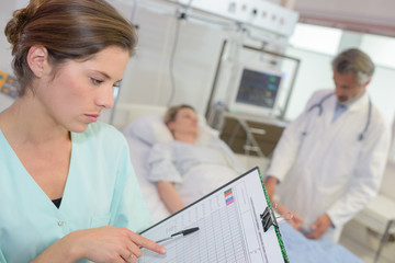 Fototapeta premium nurse with clipboard in her hands registering womans healthcare stats
