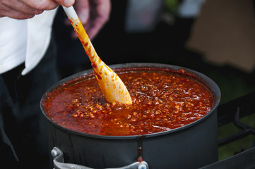 Cook Stirring a Simmering Pot of Spicy Chili - obrazy, fototapety, plakaty