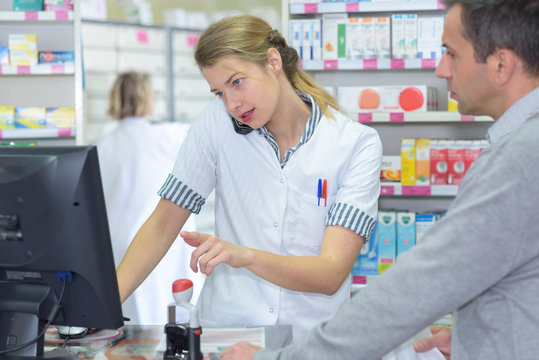 female pharmacist verifying something in front of a customer