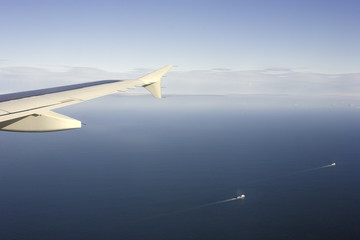 Airplane flying above the English Channel, with ships cruising on the sea