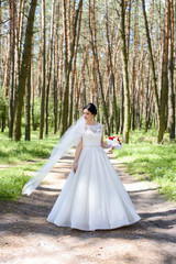 Beautiful bride perfect style. Wedding hairstyle make-up luxury wedding dress and bride's bouquet on wedding day. Beautiful bride outdoors in a forest.