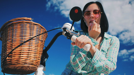 Woman is painting lipstick, woman with lipstick, woman is looking in bicycle mirror