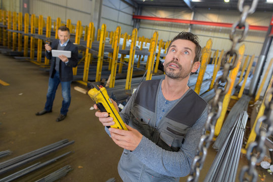 worker looking up in warehouse while holding digital device