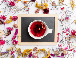 Cup of organic fruit tea and board with herbs