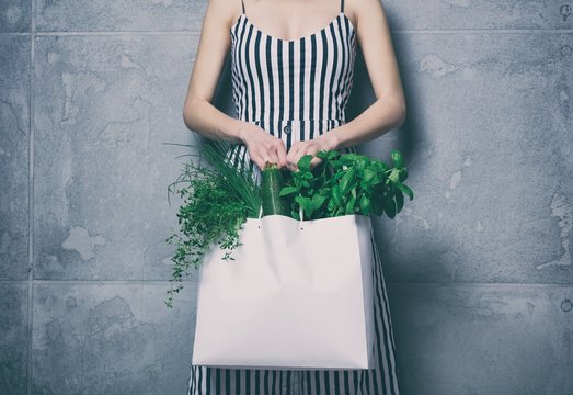 woman holding white bag with organic herbs