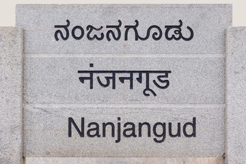 Nanjangud, India - October 26, 2013: Gray stone sign at entrance of the city showing its name in Hindi, Kannada and English languages.