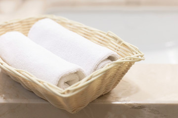 Two rolled white hand towels in rectangular basket
