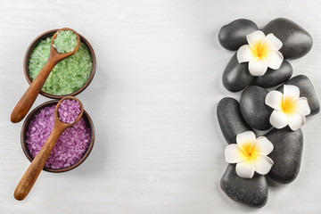 Spa stones with plumeria flowers and sea salt on light background