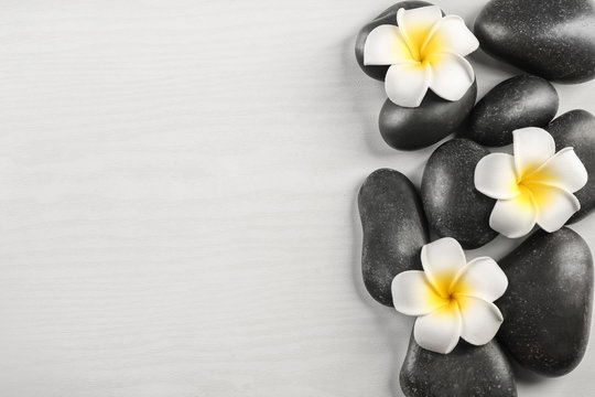 Spa stones with plumeria flowers on light background
