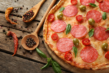 Pizza with salami on wooden background
