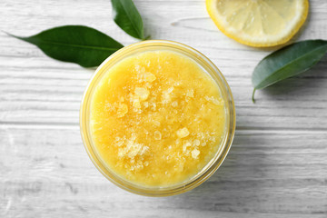 Glass bowl with lemon scrub and sea salt on wooden background