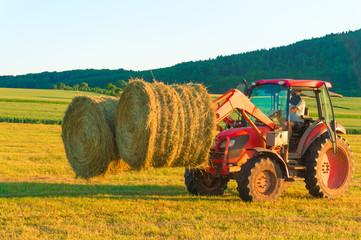 The tractor collects hay on the field