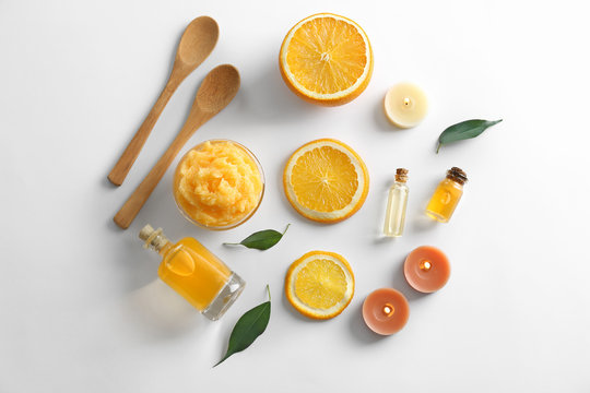 Wooden spoons, bowl with scrub, bottles of oil, candles and orange slices isolated on white