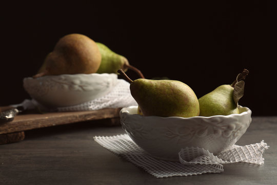 Green pears in plate on black background