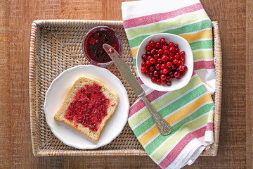 Tasty toast with berry jam for breakfast on wicker tray