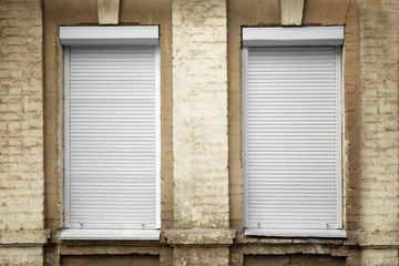 White windows with closed roller blinds in wall