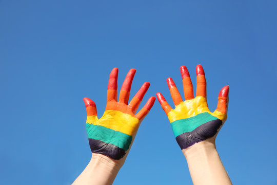 Lesbian couple with painted hands on sky background