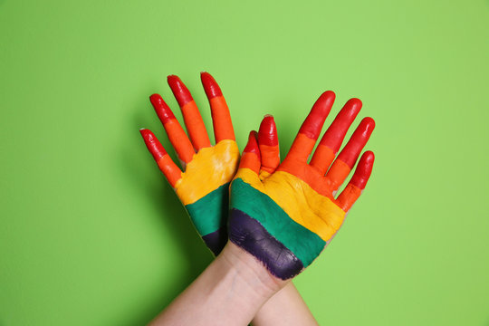 Lesbian couple with painted hands on color background