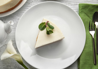 Plate with piece of delicious cheesecake on table