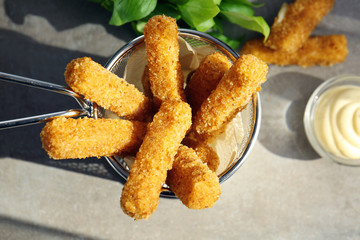 Metal basket with cheese sticks on table