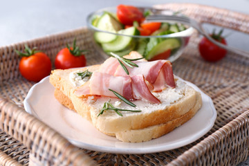 Tasty sandwich and salad for breakfast on wicker tray