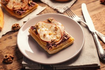 Plate with delicious pastry and flatware on wooden table