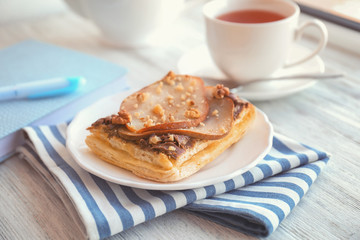 Plate with delicious pastry and striped napkin on wooden table