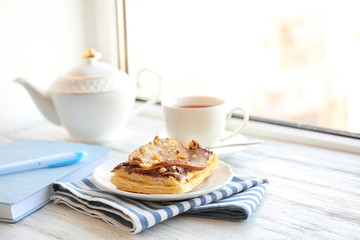 Plate with delicious pastry and striped napkin on wooden table