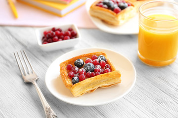 Plate with delicious pastry, fork and glass of juice on wooden table