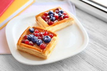 Plate with delicious pastries on wooden background