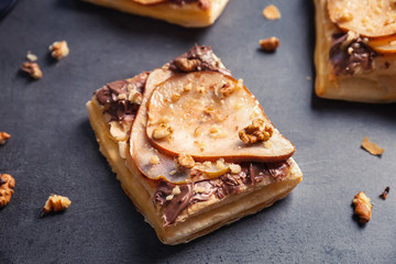 Delicious pastry with chocolate, pear and nuts on grey background