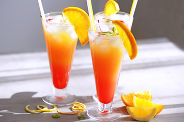 Glasses of Tequila Sunrise cocktail with citrus slices on table
