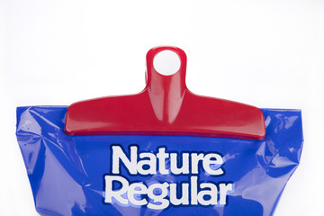 Red plastic chips bag clip on a blue bag of chips. Bag clip and chips bag isolated on white background.