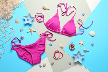 Bright bikini and seashells on color background