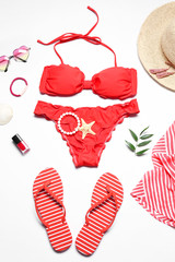 Red bikini and beach accessories on white background